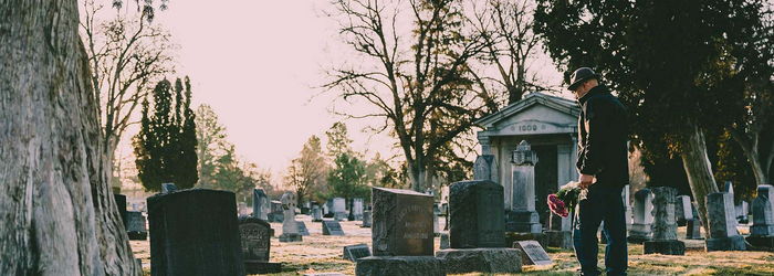 Mann vor einem Grabstein auf einem Friedhof